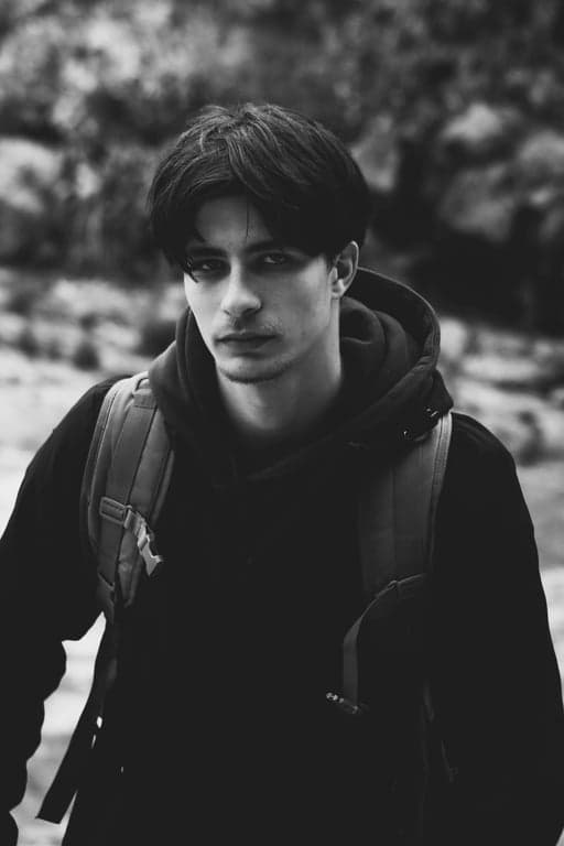 a portrait of a man edited in a Korean men hairstyle style, so that the top hair is medium length and straight, sides and back are cut short and close to the scalp following a Korean two-block haircut structure, with no curls or waves anywhere, no fringe covering the forehead, and unchanged face and original lighting