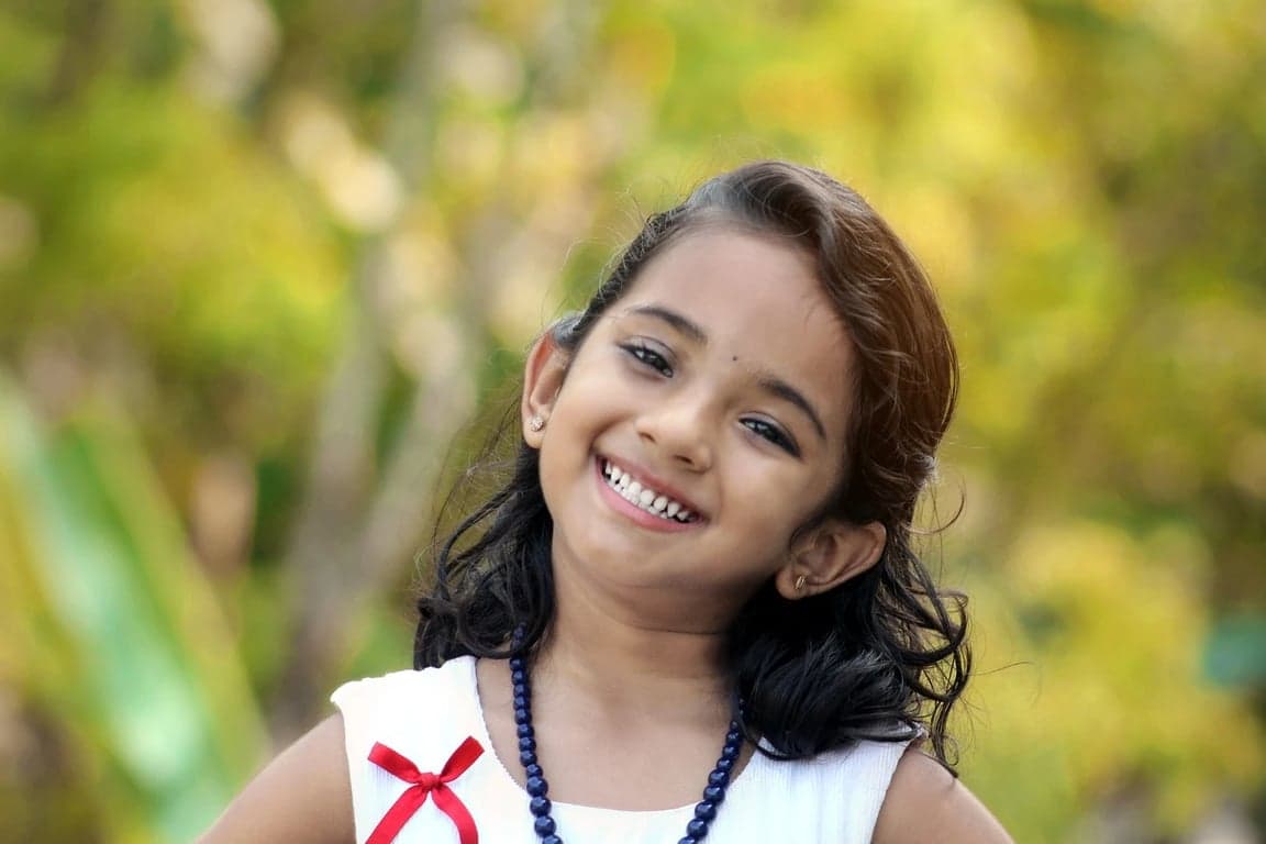 AI teeth whitening filter before photo - little girl smiling in park