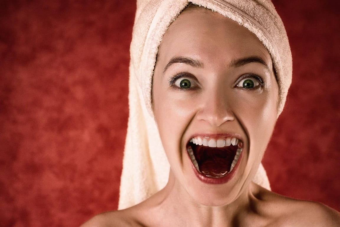 AI teeth whitening filter before photo - excited woman with red background showing big smile