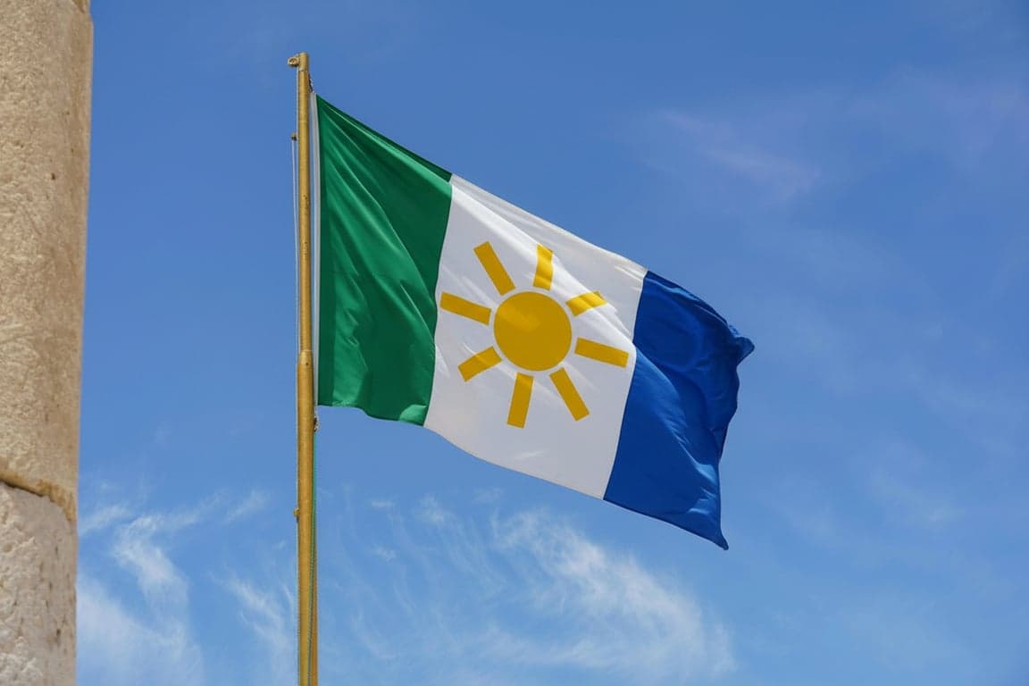A tricolor vertical triband flag with geometric symbols, colors representing earth (green), peace (white), and knowledge (blue), a central stylized sun emblem, simple and bold.