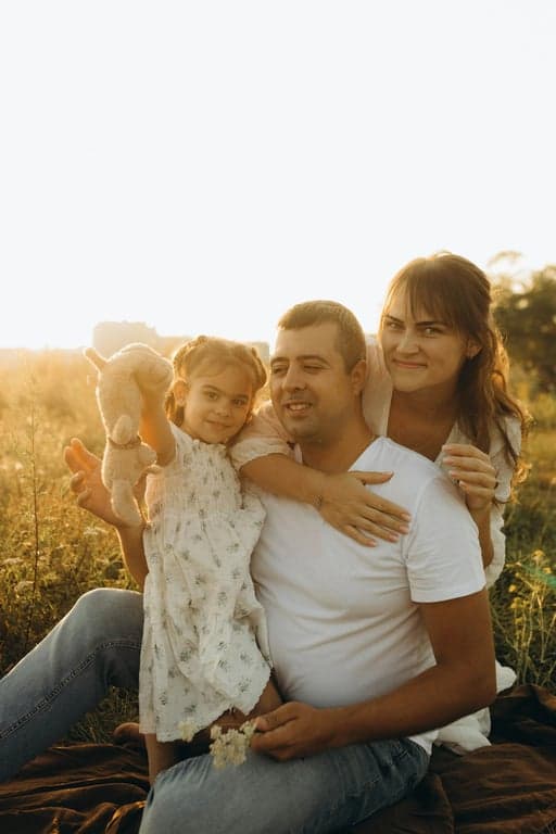 a portrait of a family transformed into a summer-themed family portrait, all members wearing light casual summer clothing such as linen shirts and dresses in soft bright colors, placed in a sunny outdoor environment like a park or beach, using relaxed seated or walking poses, natural smiles, and a fresh joyful atmosphere