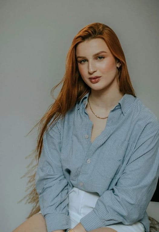 a portrait of a person wearing a Korean-inspired layered outfit with oversized knit top, fluid midi skirt, soft drape, controlled volume, neutral tones, natural posture, clean indoor lighting