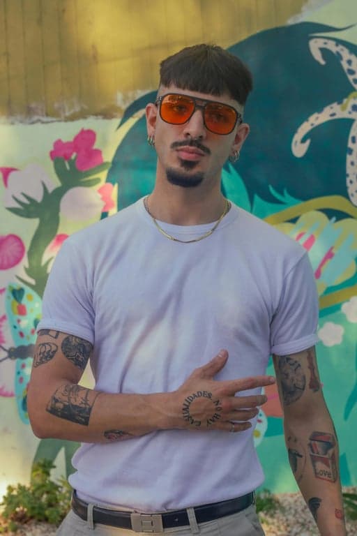 Convert the original person into a Hello Kitty parallel world plush character with a cat face. Preserve pose and outfit shape, render the character as a soft plush toy with rounded forms, fuzzy fabric texture, stitched-like edges, and gentle pastel colors, styled like official Sanrio plush merchandise.