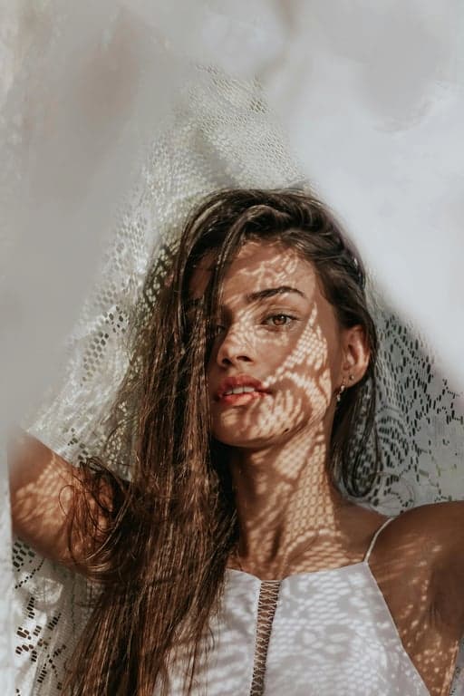 a portrait of a woman wearing a hooded sweatshirt and leggings, sitting on a pile of pumpkins at a farm