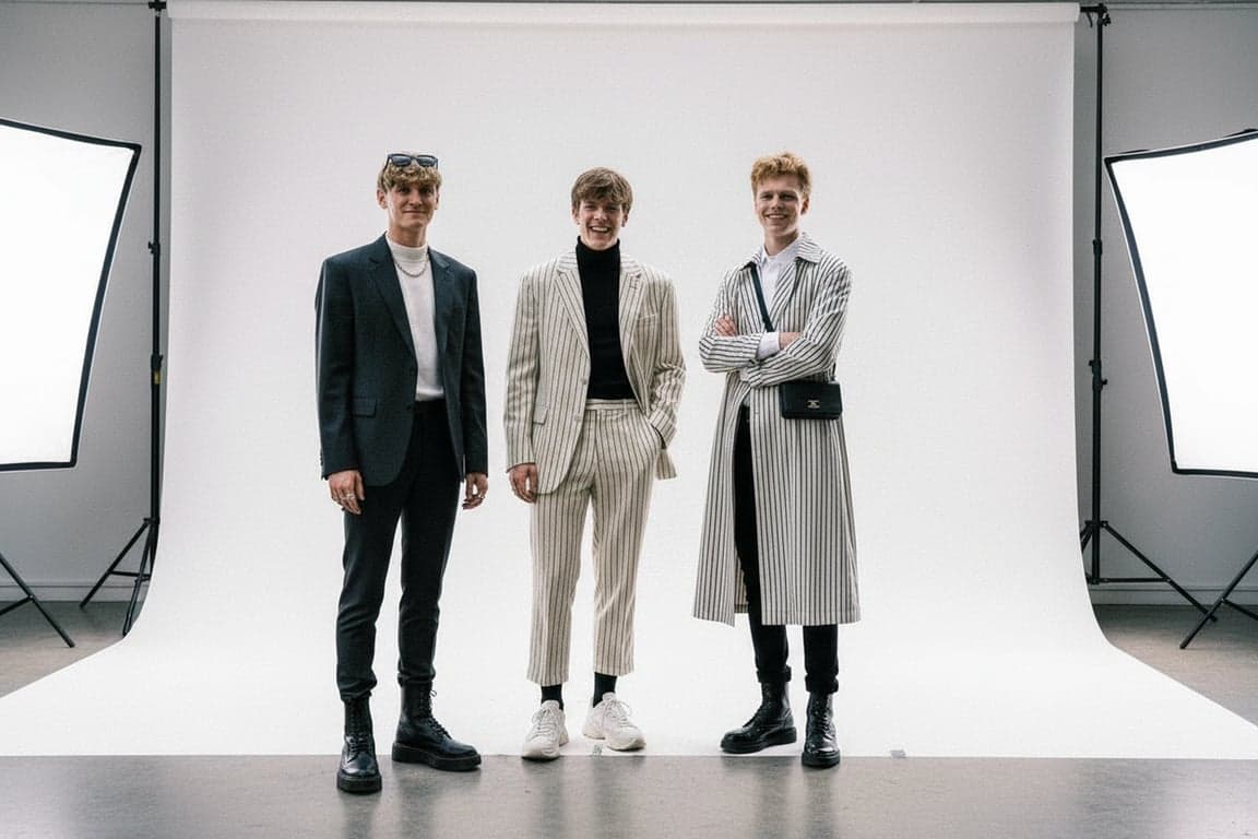 a portrait of a male group styled in modern K-pop boy group outfits, featuring refined tailoring, coordinated silhouettes, clear outfit structure, composed posture, and minimal studio background