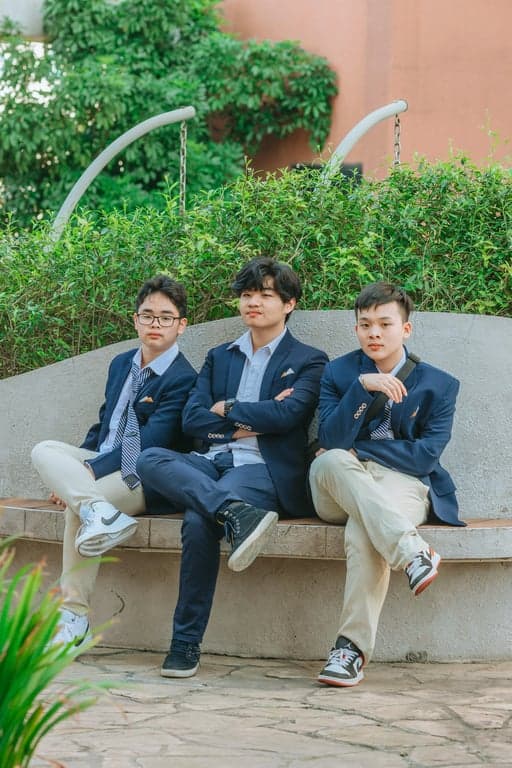 a portrait of a group styled as a K-pop boy group editorial shoot, wearing fashion-forward tailored outfits, clean silhouettes, layered garments, refined fabric textures, intentional styling differences between members, composed poses, controlled studio lighting, and a clean editorial background