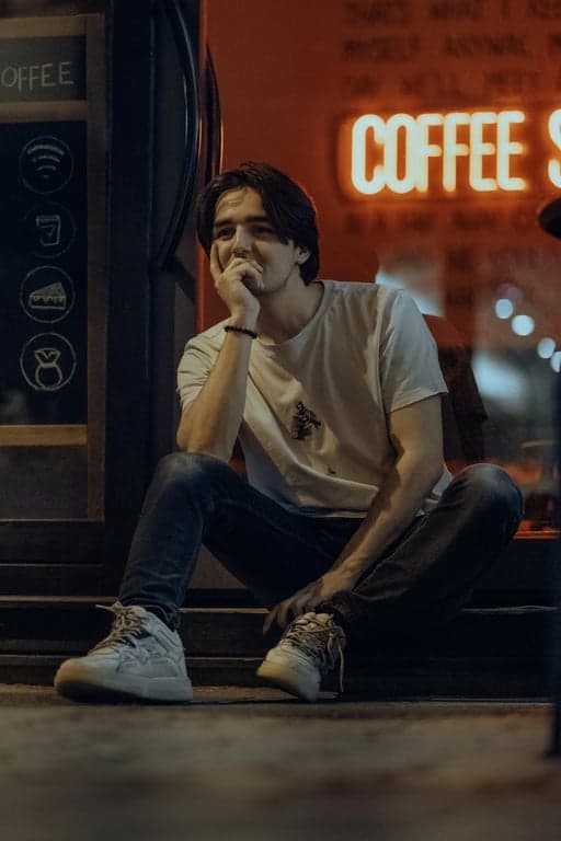 a GTA-inspired illustration that maintains the original person’s facial structure and clothing silhouette, stylizes details into sharp-edged painterly forms, applies warm saturated colors, strong shadow blocks, and a street-oriented background consistent with GTA urban aesthetics