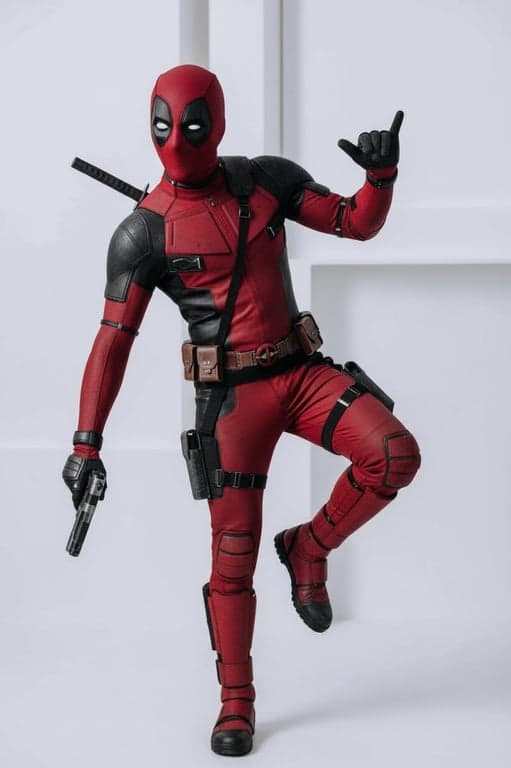 a portrait of a person as Deadpool in a dynamic pose, wearing the full red suit, tactical belts, and holding guns with a playful attitude