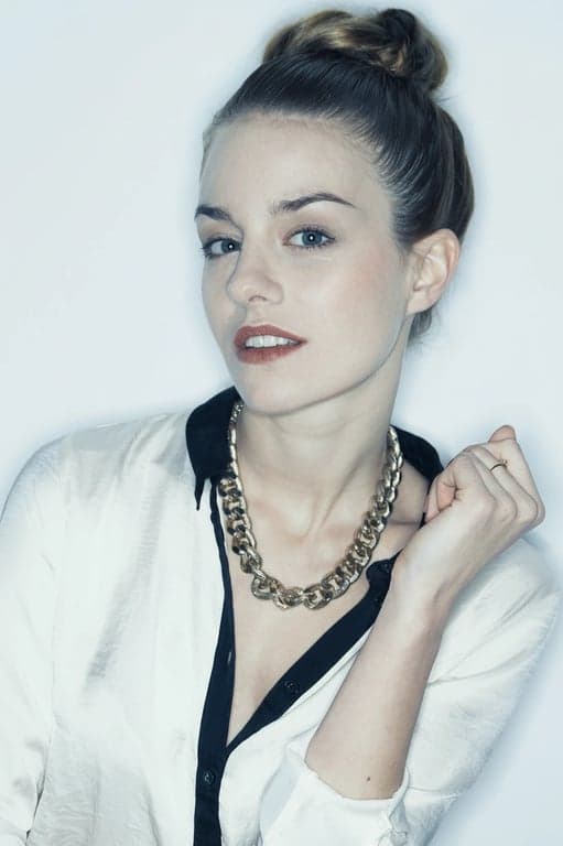 A cool aesthetic headshot of a woman, desaturated warm colors, emphasis on blues and greys, soft flat lighting, professional and sleek look.