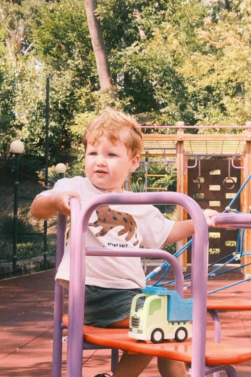 A child enjoying tea in a courtyard, painted in the warm, narrative style of a classical Chinese genre painting, with attention to domestic details and textures.