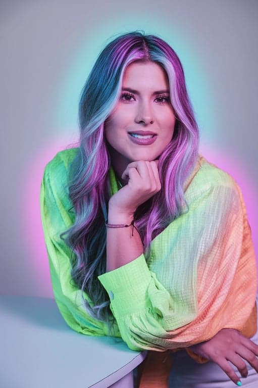 a portrait of a person where their hair and clothing emit a soft, self-generated neon glow in contrasting electric colors