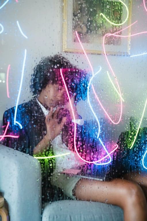 a portrait of a person looking through a glass pane covered in glowing neon condensation droplets and abstract reflections