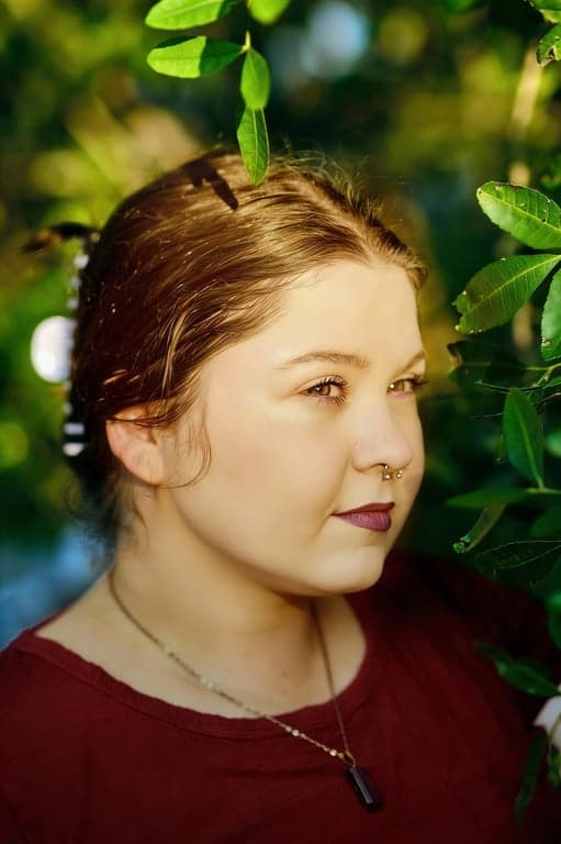 a portrait of a person enhanced to create a visibly slimmer lower face by aggressively reducing under-chin volume and reinforcing jawline separation; reshape the submental contour so the chin reads sharper and lighter; maintain original facial proportions and identity; preserve pores and skin detail; avoid over-blurring; do not alter background or scene; the improvement should be immediately noticeable without comparison