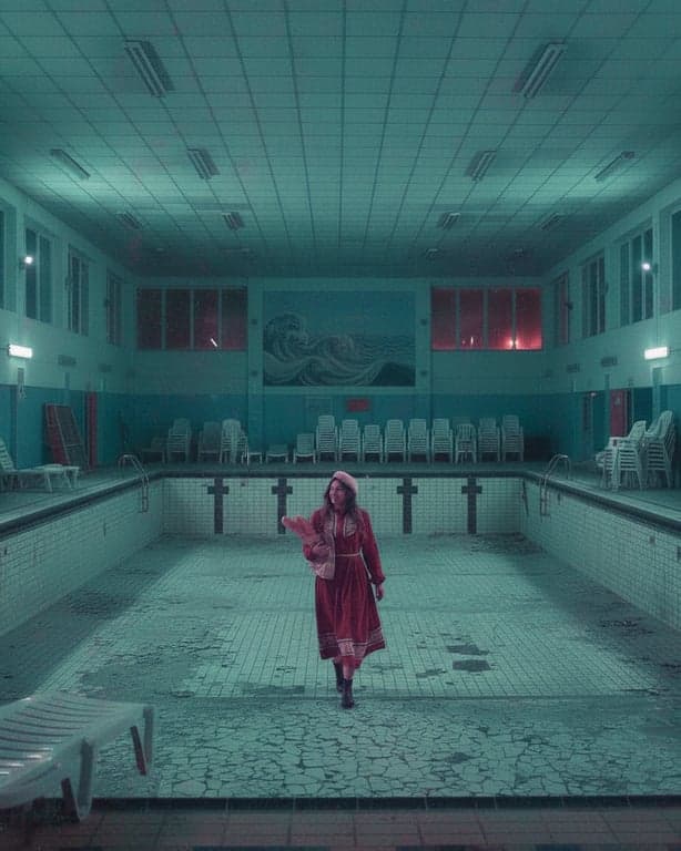 a portrait of a person in a liminal space (empty mall, pool at night) with heavy teal and pink tint and a sense of nostalgia