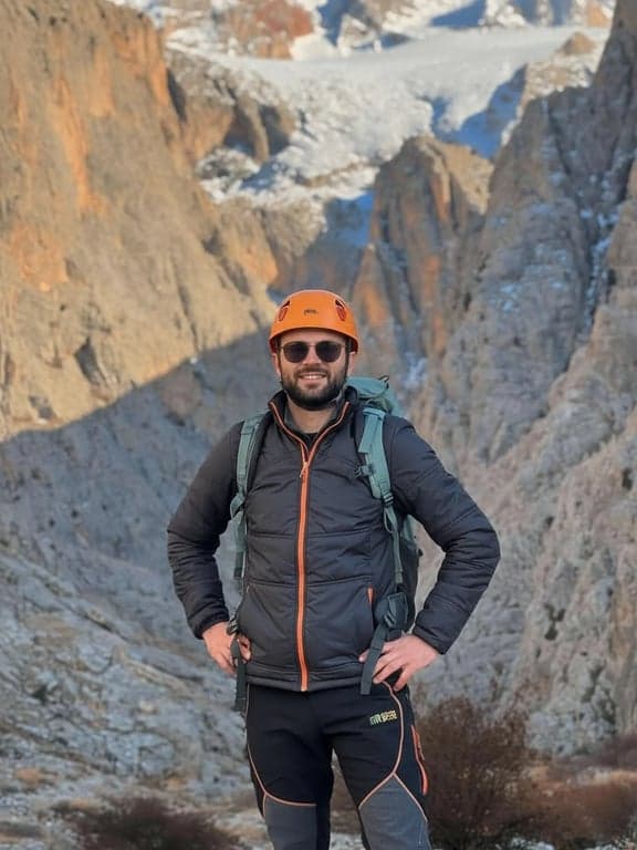 create a dating-ready profile photo by correcting camera angle to eye level, improving posture to appear open and confident, redesigning lighting to remove harsh facial shadows, enhancing eye visibility, sharpening facial detail while preserving skin texture, simplifying the background, and ensuring the result looks clearly more flattering and intentional than the original casual photo