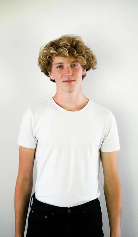 A realistic photo edit of a man, aging reduction while keeping character lines, natural hair color enhancement, realistic clothing detail sharpening, balanced exposure.