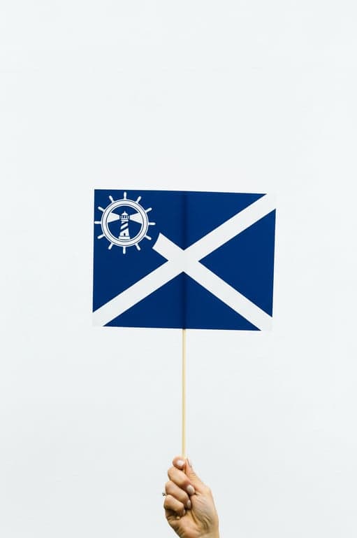 A navy blue flag with a white saltire (diagonal cross), a complex but clear emblem (a lighthouse within a ship's wheel) in the canton, clean and recognizable at sea.