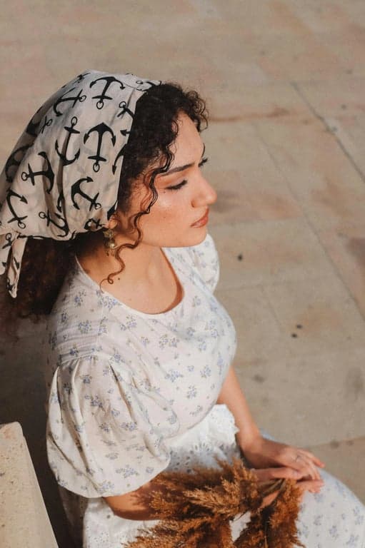 a portrait of a person styled in an anime war-drama aesthetic, wearing utilitarian clothing with structured folds, restrained colors, weathered texture, and intense focused expression