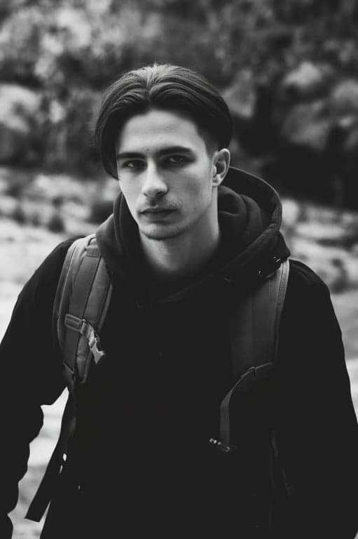 a portrait of a man edited in a Korean men hairstyle style, so that the top hair is medium length and straight, sides and back are cut short and close to the scalp following a Korean two-block haircut structure, with no curls or waves anywhere, no fringe covering the forehead, and unchanged face and original lighting