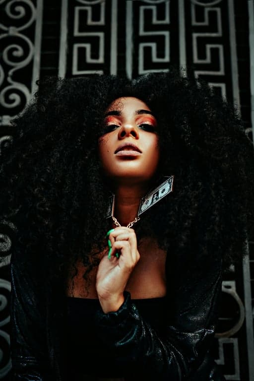 A close-up portrait of a woman converted into monochrome ASCII art, using a dense mix of characters (like @, #, %, *, `, .) to create gradients and facial details.