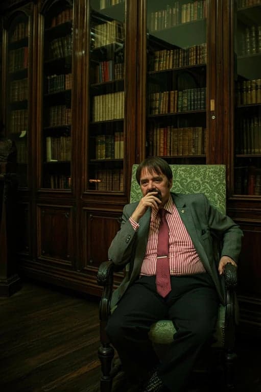 a portrait of a person transformed by lowering the hairline substantially, adding hair coverage to the forehead so the head shape looks fuller and the facial proportions appear smaller