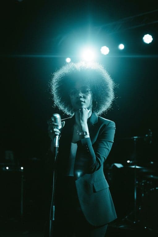 A concert photo style from the 1970s, with heavy grain, deep shadows, bright stage lights causing lens flare, and a slightly cyan shift in the blacks.