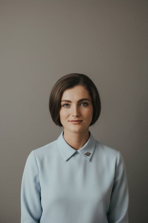 A studio portrait emulating the clean, minimalist style of 1960s corporate or yearbook photography, with even lighting, a neutral grey backdrop, and a sincere expression.