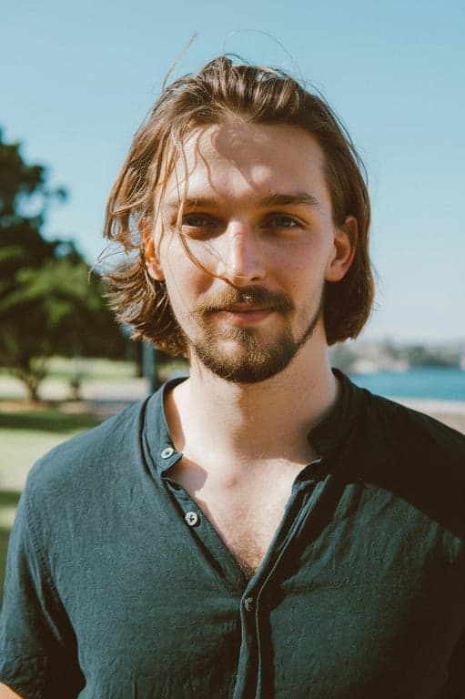 a portrait of a man edited to feature a horseshoe goatee, where the mustache extends downwards around the mouth to connect with the chin beard