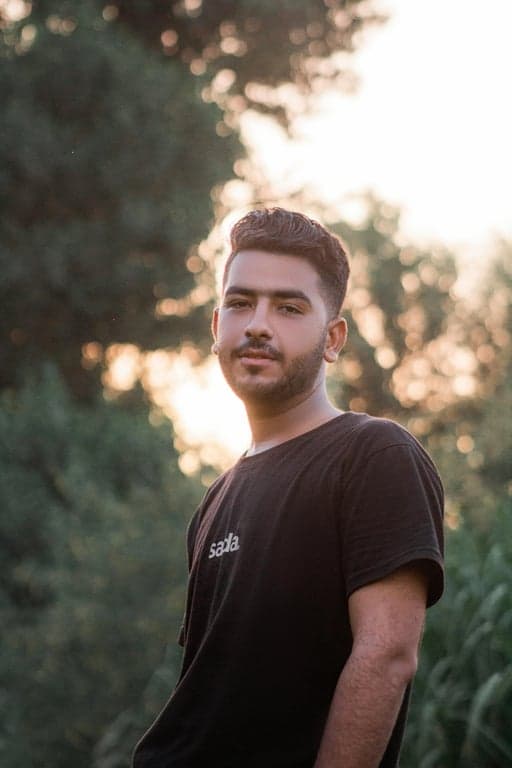 a portrait of a man edited in a Korean wavy perm hairstyle style, so that the top hair has large loose waves forming visible curls typical of Korean men perm looks, while the sides and back are short and straight, with curl texture appearing only on the top section, and unchanged face and original lighting
